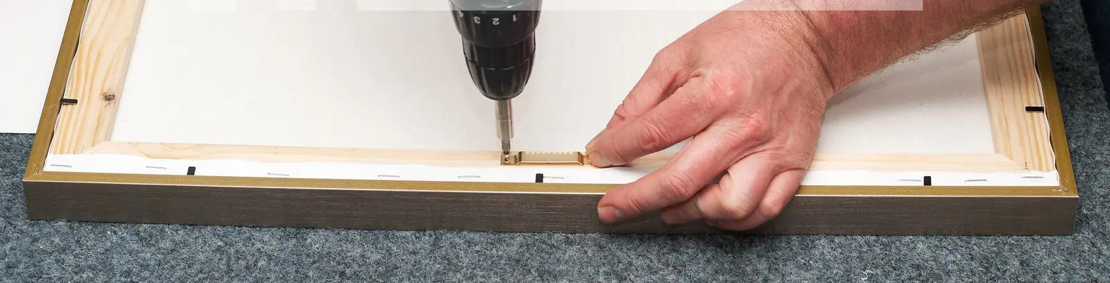 Framer fixing the backing of a frame with a drill