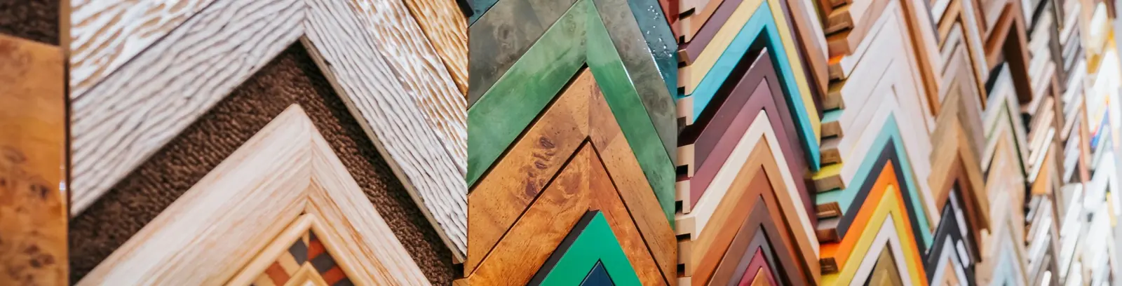 Wall of frame moulding corner samples in wood, gold and colour finishes